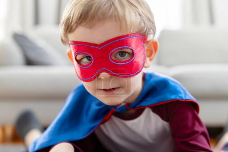 Nahaufnahme eines Kleinkindes in einem Superheldenkostüm mit Maske, das Stärke und Verspieltheit darstellt.