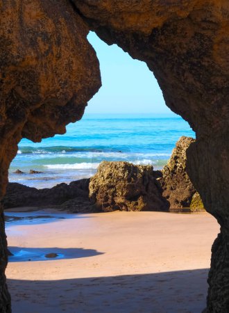 A hole in a cliff opens a view to the ocean in Algarve Portugal