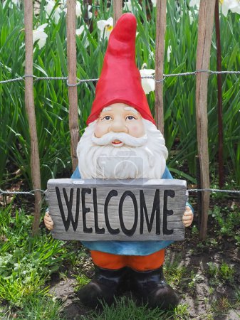 Garden dwarf with a red pointed hat holding a welcome sign
