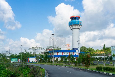 Photo for Tanjungpinang, Indonesia - January 28, 2024 : The flight management air control tower and passenger terminal at Raja Haji Fisabilillah International Airport with airplanes flying in the clear sky - Royalty Free Image