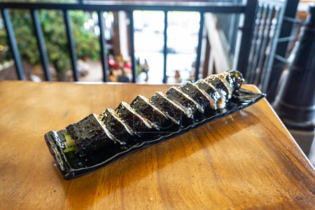 Los rollos de sushi coreanos (kimbap o gimbap) se cortan en trozos pequeños y se sirven en un plato largo. El plato está hecho de arroz y otros ingredientes enrollados en hojas de algas o rollos de primavera.