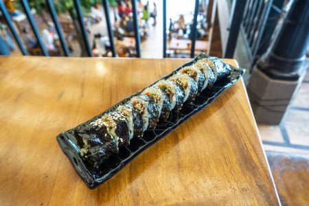 Téléchargez les photos : Les rouleaux de sushi coréens (kimbap ou gimbap) sont coupés en petits morceaux et servis sur une assiette longue. Le plat est fabriqué à partir de riz et d'autres ingrédients roulés dans des feuilles d'algues ou des rouleaux de printemps - en image libre de droit