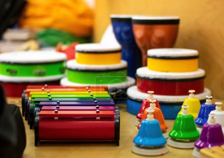 a closeup of colorful musical instruments and drums on a shelf with a blurry background