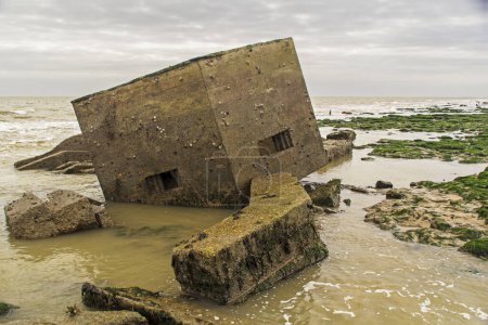 Photo for WW2 pillbox defences that has slippen into the sea due to coastal erosion, looming out of the water like a giant robot. - Royalty Free Image