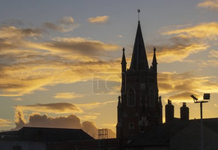 Téléchargez les photos : St Neots United Reformed Church Silhouette face à un magnifique coucher de soleil doré. Photo de haute qualité - en image libre de droit