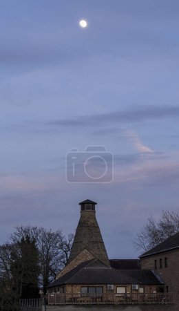 Foto de St Neots, Reino Unido - 17 de marzo de 2019: Luna sobre la casa pasada. Atardecer en una cálida noche de primavera. Foto de alta calidad - Imagen libre de derechos