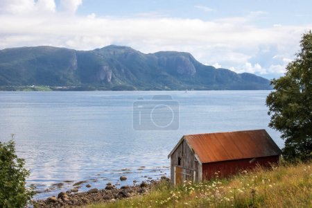 Bootshaus am Fjordufer mit Bergen im Hintergrund. Hochwertiges Foto