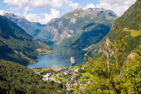Landscape view across the town of Geiranger and the Fjord with a cruise ship . High quality photo