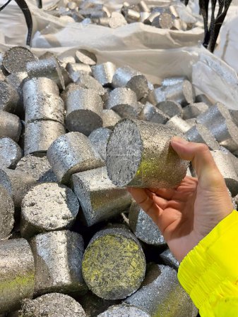 A hand holding a briquette of compressed aluminium swarf ready to be recycled. High quality photo