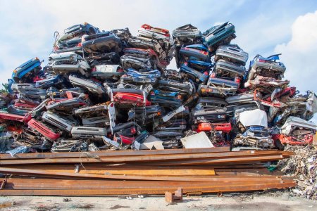 A large heap of rusty scrap cars in a junk yard ready to be recycled. High quality photo