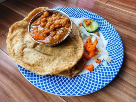Téléchargez les photos : Curry de pois chiches épicés ou Chana Masala ou Choley aux poori frits garnis d'oignon tranché et de feuille de coriandre verte - en image libre de droit