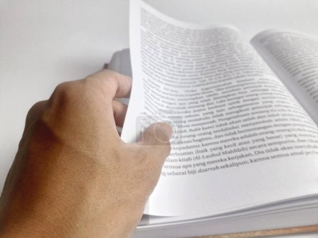 Téléchargez les photos : Un homme qui ouvre les pages d'un livre épais avec un fond blanc - en image libre de droit