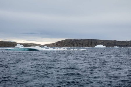 Ice structures of different shapes melting in front of the rocky island in Antarctica
