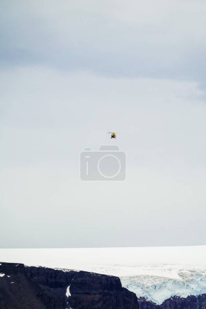 Foto de Helicóptero amarillo sobrevolando la isla Vega, Península Antártica, Antártida - Imagen libre de derechos