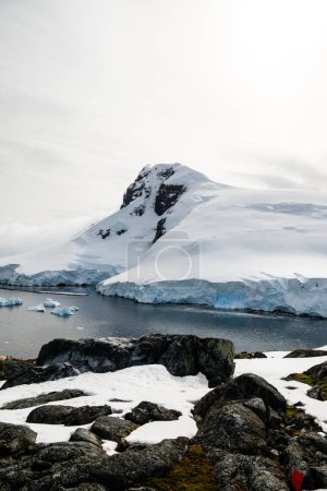 Foto de Tiro vertical de la bahía en la Isla Dos Hummock. Con montaña, rocas cubiertas de nieve y un glaciar. Paisaje antártico. - Imagen libre de derechos