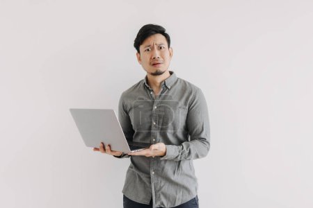 Photo for Asian man with beard wear grey shirt, dislike unsatisfied face, holding notebook hand gesture, unhappy question face looking at camera isolated over white background wall. - Royalty Free Image