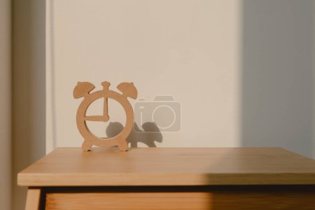 Téléchargez les photos : Photo de conception en forme d'horloge en bois, montrant l'ombre du modèle de montre, mettant sur chaise en bois avec lumière du soleil dans la pièce d'appartement. - en image libre de droit