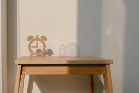 Foto de Foto de diseño de forma de reloj de madera, que muestra la sombra del modelo de reloj, poner en la silla de madera con luz solar en la habitación del apartamento. - Imagen libre de derechos