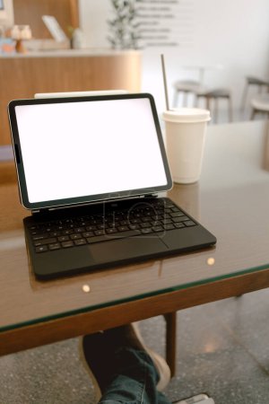 Téléchargez les photos : Vue des jambes de l'homme, montrant son ordinateur portable avec écran de banque blanche tout en travaillant en ligne au café. - en image libre de droit
