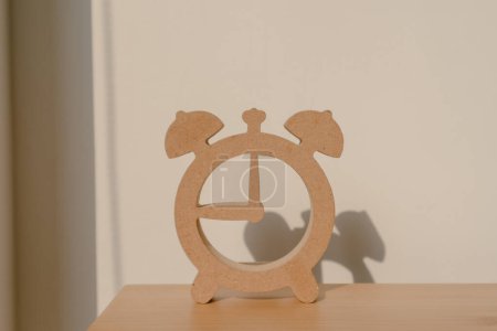 Téléchargez les photos : Photo de conception en forme d'horloge en bois, montrant l'ombre du modèle de montre, mettant sur chaise en bois avec lumière du soleil dans la pièce d'appartement. - en image libre de droit