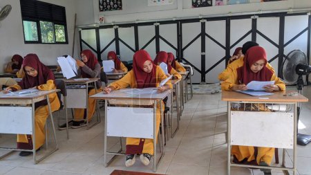 Téléchargez les photos : Ambas, Indonésie-mars 22, 2024 : lycéens travaillant sur des questions d'évaluation à l'intérieur - en image libre de droit