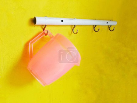 A hanger for storing cooking utensils attached to the wall with a yellow background