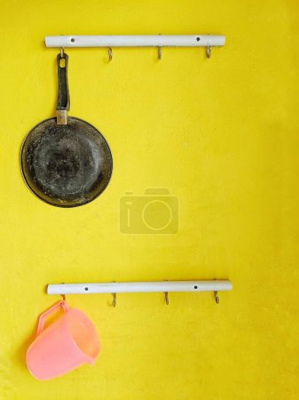 A hanger for storing cooking utensils attached to the wall with a yellow background