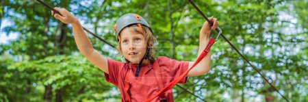 Foto de BANNER, FORMATO LARGO Niño feliz en un casco, adolescente saludable escolar disfrutando de la actividad en un parque de aventura de escalada en un día de verano. - Imagen libre de derechos