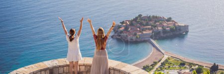 Photo for BANNER, LONG FORMAT Two Woman tourist on background of beautiful view of the island of St. Stephen, Sveti Stefan on the Budva Riviera, Budva, Montenegro. Travel to Montenegro concept. - Royalty Free Image
