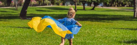 Foto de BANNER, FORMATO LARGO Chica ucraniana con bandera de Ucrania. Afuera. Concepto de problema de la guerra en Europa, apoyo a las familias y los niños, emigrantes, emigración, patriotismo, maternidad. - Imagen libre de derechos