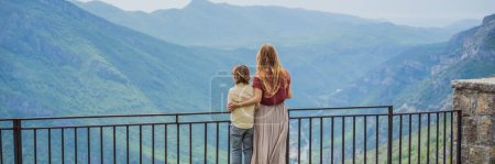 Photo for BANNER, LONG FORMAT Mother and son tourists on background of Blue river running through green valley toward distant mountains. Beautiful mountains of Montenegro and the river Cievna. - Royalty Free Image