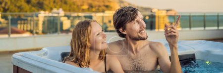 Foto de BANNER, FORMATO LARGO Retrato de la joven y despreocupada feliz pareja sonriente relajarse en la bañera de hidromasaje durante el disfrute de la vida feliz momento de viaje de vacaciones en el fondo de grandes montañas verdes. - Imagen libre de derechos