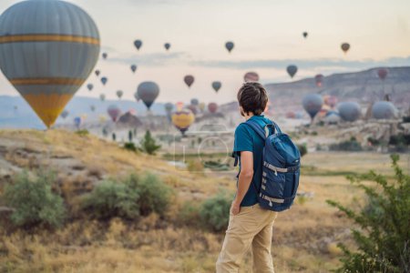 Foto de Turista mirando globos aerostáticos en Capadocia, Turquía. Feliz viaje en Turquía concepto. Hombre en la cima de una montaña disfrutando de una vista maravillosa. - Imagen libre de derechos