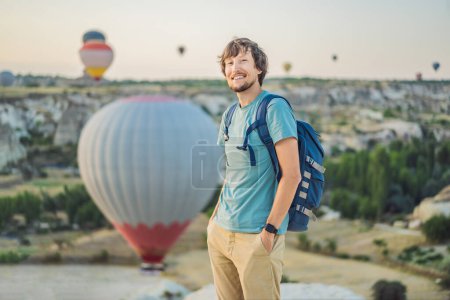 Foto de Turista mirando globos aerostáticos en Capadocia, Turquía. Feliz viaje en Turquía concepto. Hombre en la cima de una montaña disfrutando de una vista maravillosa. - Imagen libre de derechos