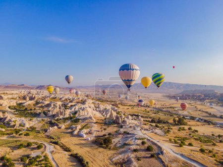 Photo for Colorful hot air balloons flying over at fairy chimneys valley in Nevsehir, Goreme, Cappadocia Turkey. Spectacular panoramic drone view of the underground city and ballooning tourism. High quality. - Royalty Free Image