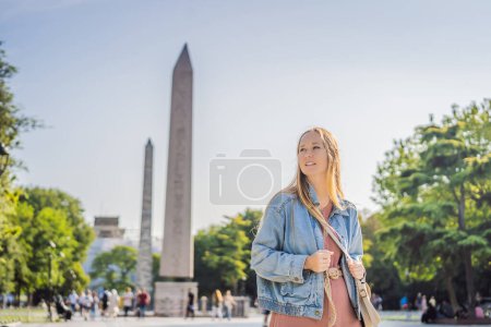 Photo for Woman Tourist in Istanbul against the background of Obelisk of Theodosius is the Ancient Egyptian obelisk of Pharaoh Thutmose III places in the Hippodrome of Constantinople, Turkey. Theodosius - Royalty Free Image