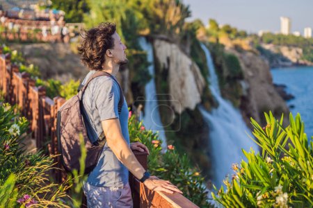Téléchargez les photos : Touriste homme sur le fond de la cascade de Duden à Antalya. Lieux célèbres de Turquie. Les basses chutes de Duden tombent d'une falaise rocheuse tombant d'environ 40 m dans la mer Méditerranée dans une eau étonnante - en image libre de droit
