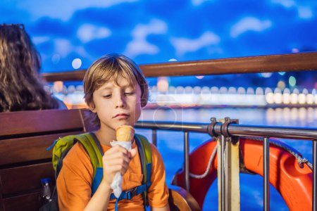 Photo for Boy tourist boy eating turkish ice cream by ferry in the Bosphorus. Traveling with kids concept. - Royalty Free Image