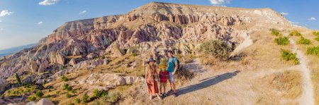 BANNER, LONG FORMAT Happy family mother, father and son tourists exploring valley with rock formations and fairy caves near Goreme in Cappadocia Turkey.