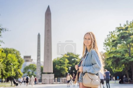 Photo for Woman Tourist in Istanbul against the background of Obelisk of Theodosius is the Ancient Egyptian obelisk of Pharaoh Thutmose III places in the Hippodrome of Constantinople, Turkey. Theodosius - Royalty Free Image