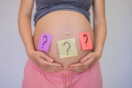 Wahl des Babynamens. Verwirrte Schwangere mit Fragezeichen auf Papieraufklebern am Bauch.