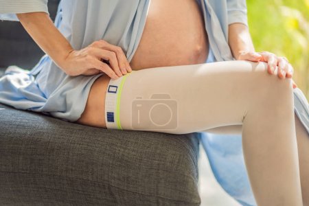 Un contenido y una mujer embarazada cómoda que usa medias de compresión, lo que garantiza una mejor salud de las piernas y apoyo durante su viaje de embarazo..