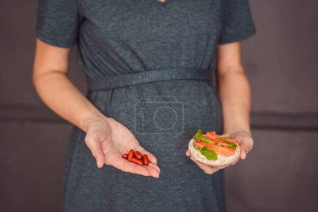 Foto de Una mujer embarazada reflexiva de más de 40 años considerando si comer pescado u optar por las cápsulas de omega 3 para un embarazo nutritivo y saludable. - Imagen libre de derechos