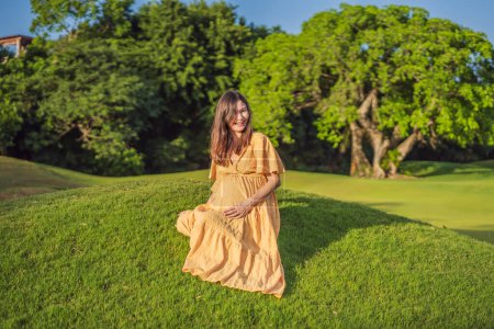 Foto de Una mujer embarazada serena y radiante después de los 40 años, rodeada de la belleza de la naturaleza en el parque, apreciando el viaje de la maternidad con una sonrisa brillante. - Imagen libre de derechos