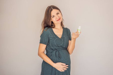 Téléchargez les photos : Femme enceinte confiante et radieuse de plus de 40 ans présentant le débat sur la grossesse et le déodorant. C'est bon ou mauvais pour les femmes enceintes. Embrassez le voyage avec des options sûres et douces. - en image libre de droit
