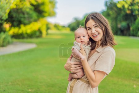 Photo for A happy 40-year-old mother cradles her newborn in a sun-drenched park. Love, family and generations in harmony. - Royalty Free Image