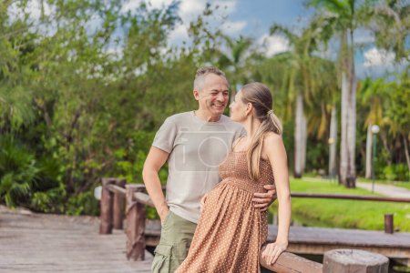 Photo for A happy, mature couple over 40, enjoying a leisurely walk in a park, their joy evident as they embrace the journey of pregnancy later in life. - Royalty Free Image