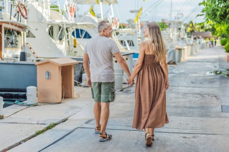 Photo for A happy, mature couple over 40, enjoying a leisurely walk on the waterfront, their joy evident as they embrace the journey of pregnancy later in life. - Royalty Free Image