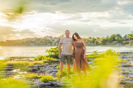 Téléchargez les photos : Un couple heureux et âgé de plus de 40 ans, profitant d'une promenade tranquille sur le front de mer Au coucher du soleil, leur joie évidente alors qu'ils embrassent le voyage de la grossesse plus tard dans la vie. - en image libre de droit