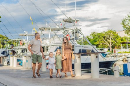 Photo for A happy, mature couple over 40 with their two daughters enjoying a leisurely walk on the waterfront, their joy evident as they embrace the journey of pregnancy later in life. - Royalty Free Image